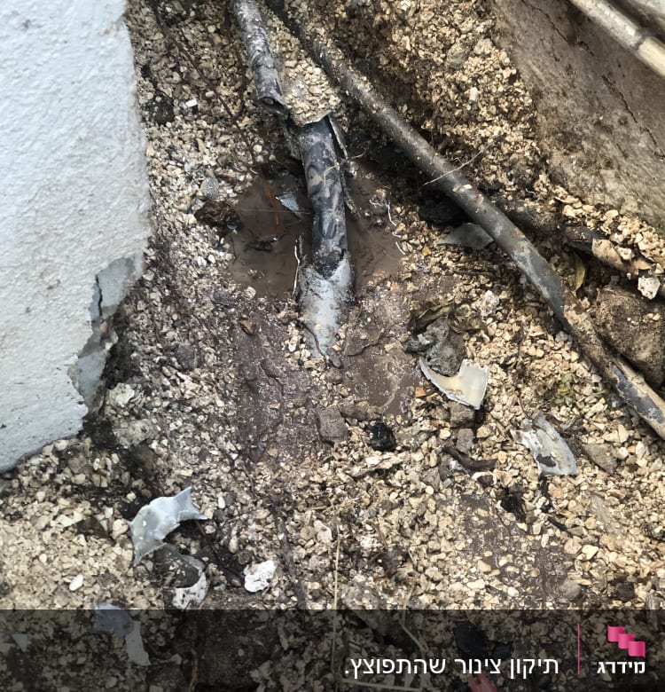 צינור שבור באדמה עם מים מסביב